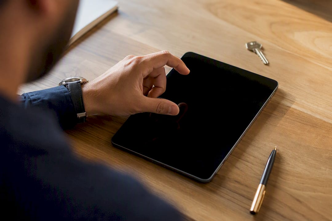 Main réglant un calendrier numérique sur une tablette avec des clés à côté