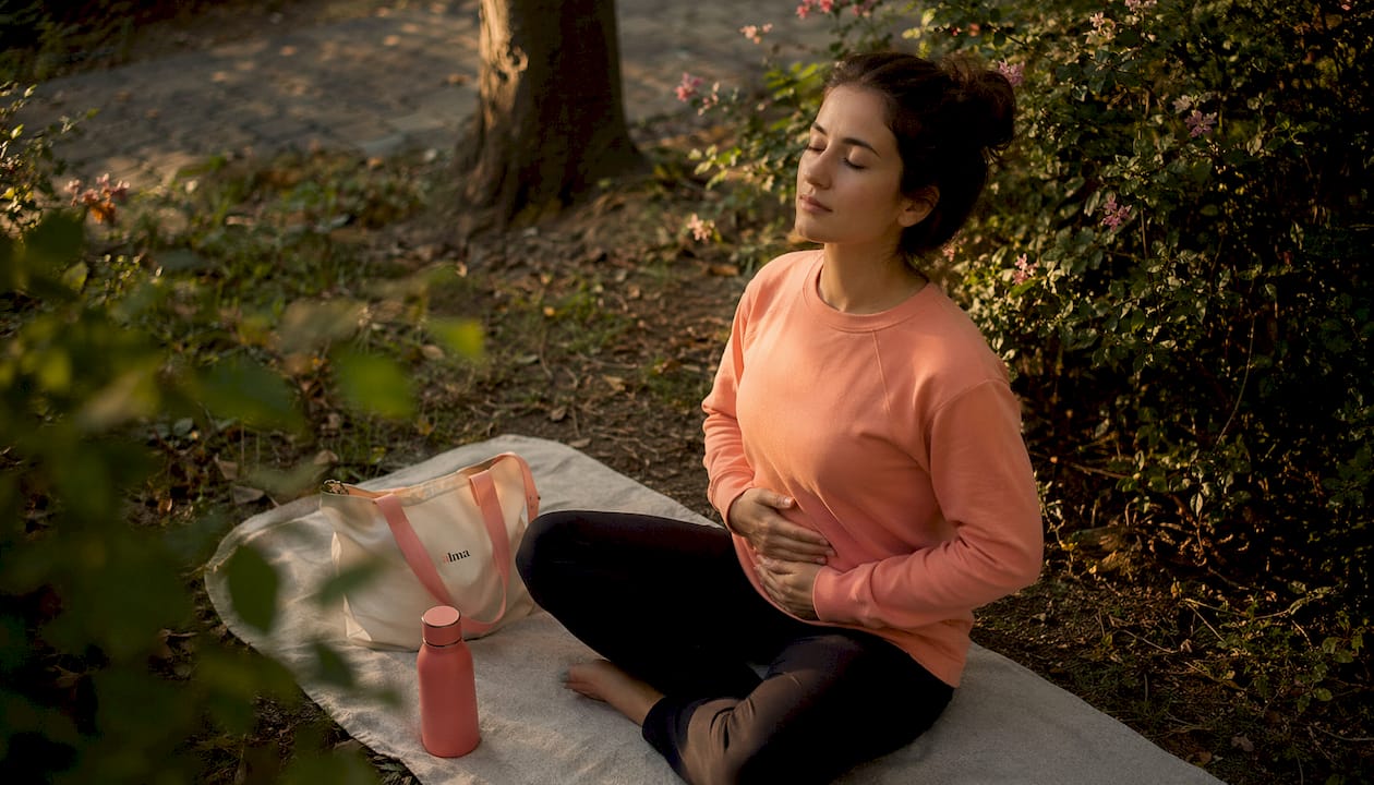 Une femme qui prend quelques minutes pour faire des exercices de respiration au travail, afin de retrouver calme et concentration.
