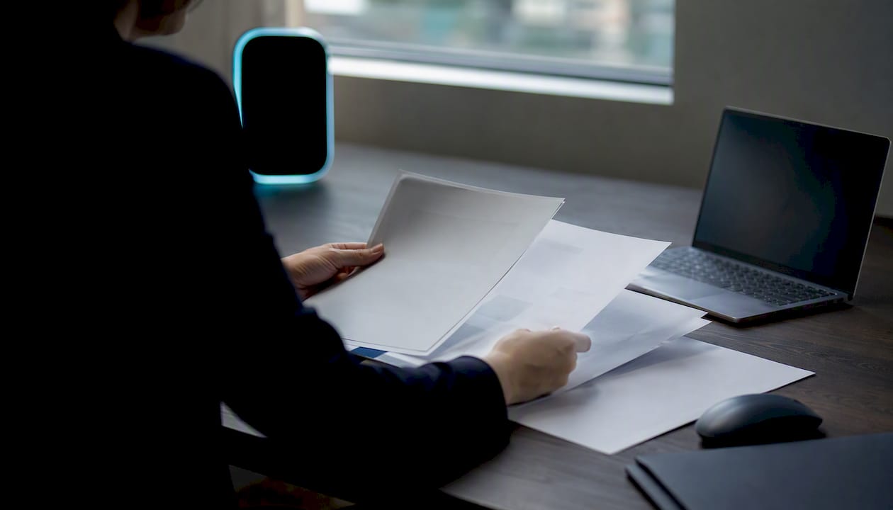 Hands reviewing candidate profiles with AI device glow
