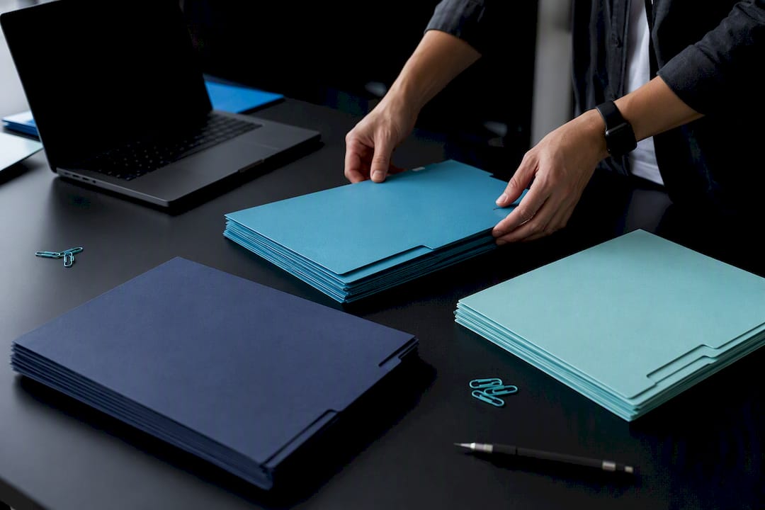 Hands sorting color-coded compliance folders