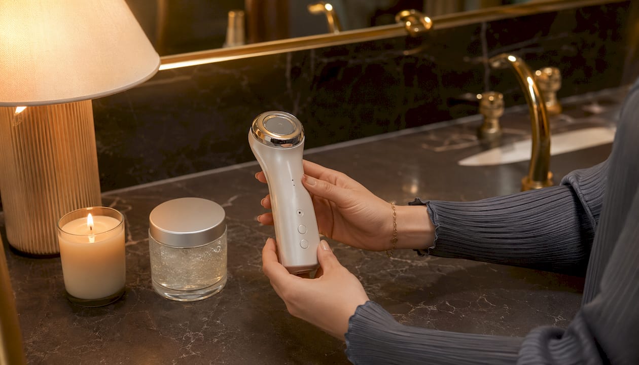 Il dispositivo CurrentBody RF tenuto in mano insieme agli accessori per la skincare