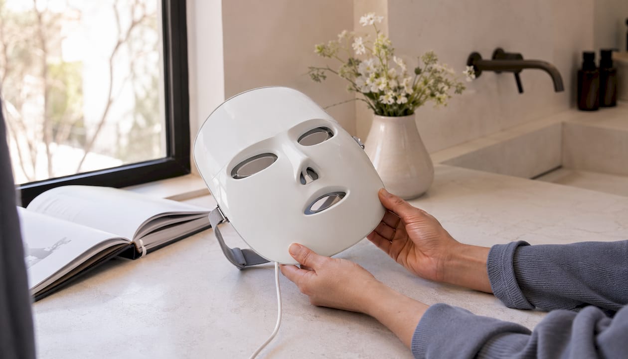Unas manos sujetan una mascarilla de terapia LED que está apagada.