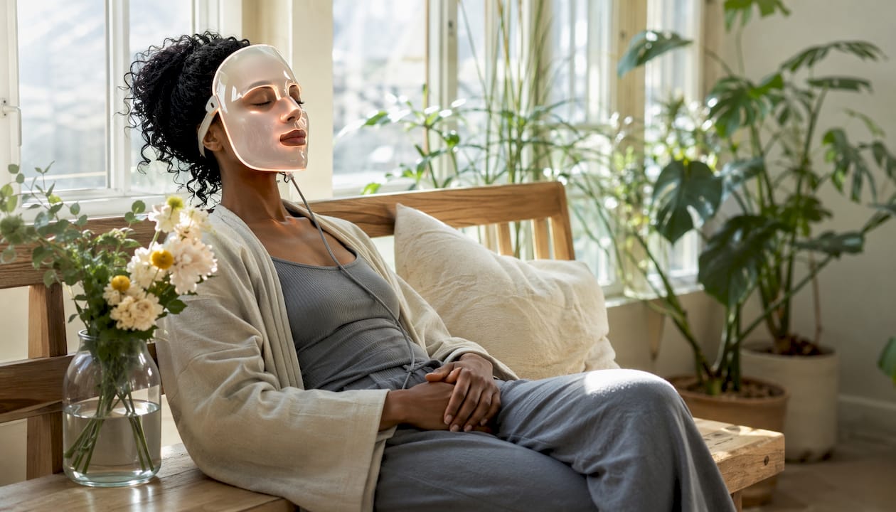 Woman relaxing with LED facial mask in bedroom