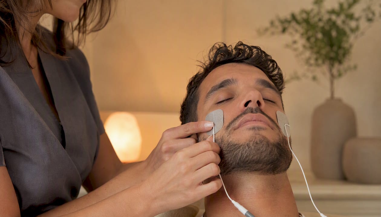 Application d’électrodes EMS sur le visage à l’aide de la main