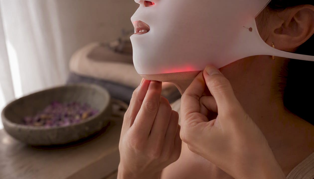 Hand adjusting silicone LED mask on face side
