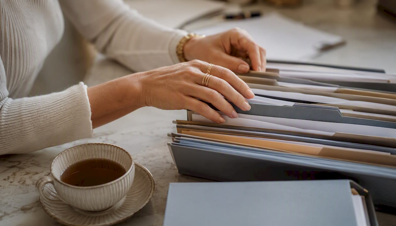 Des mains trient des dossiers remplis de documents administratifs.