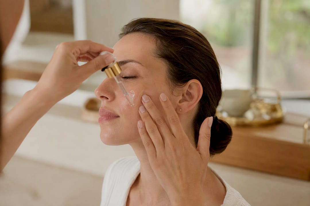 Manos aplicando sérum sobre el rostro limpio