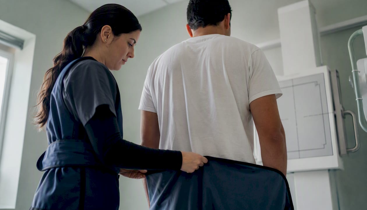 Technician positioning patient for chest X-ray