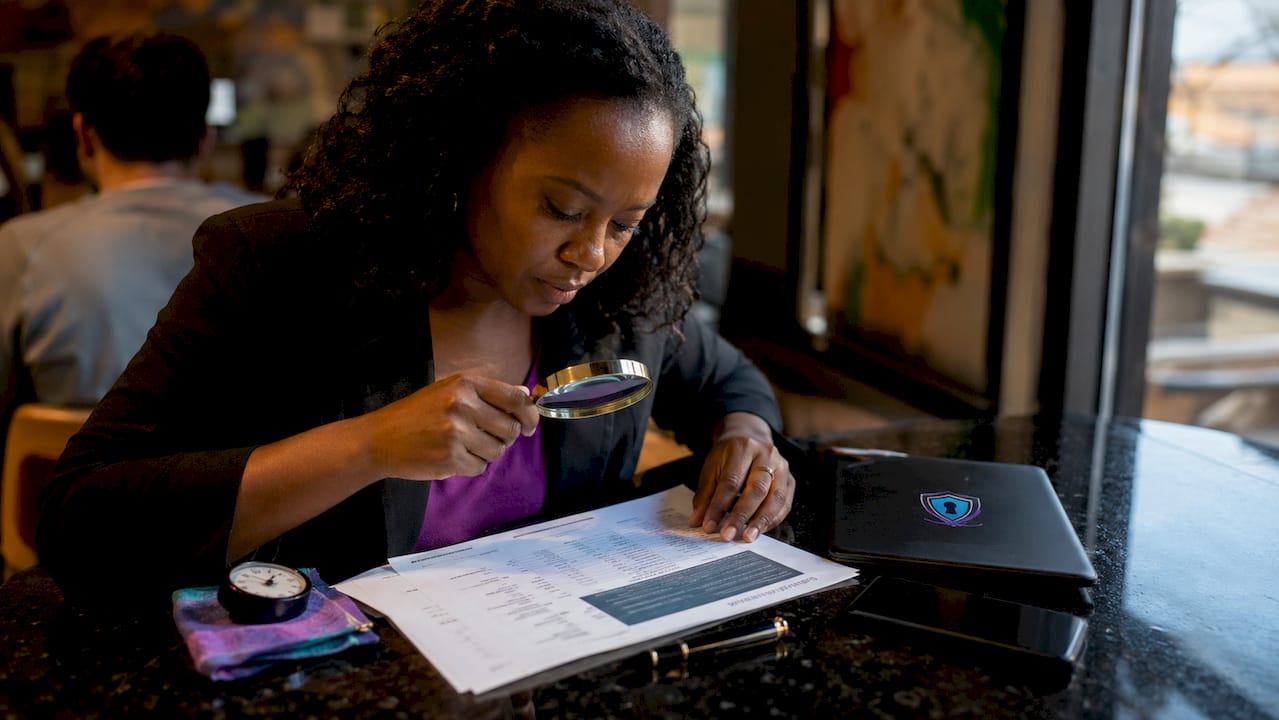 Hands examining printed blockchain ledger with magnifier