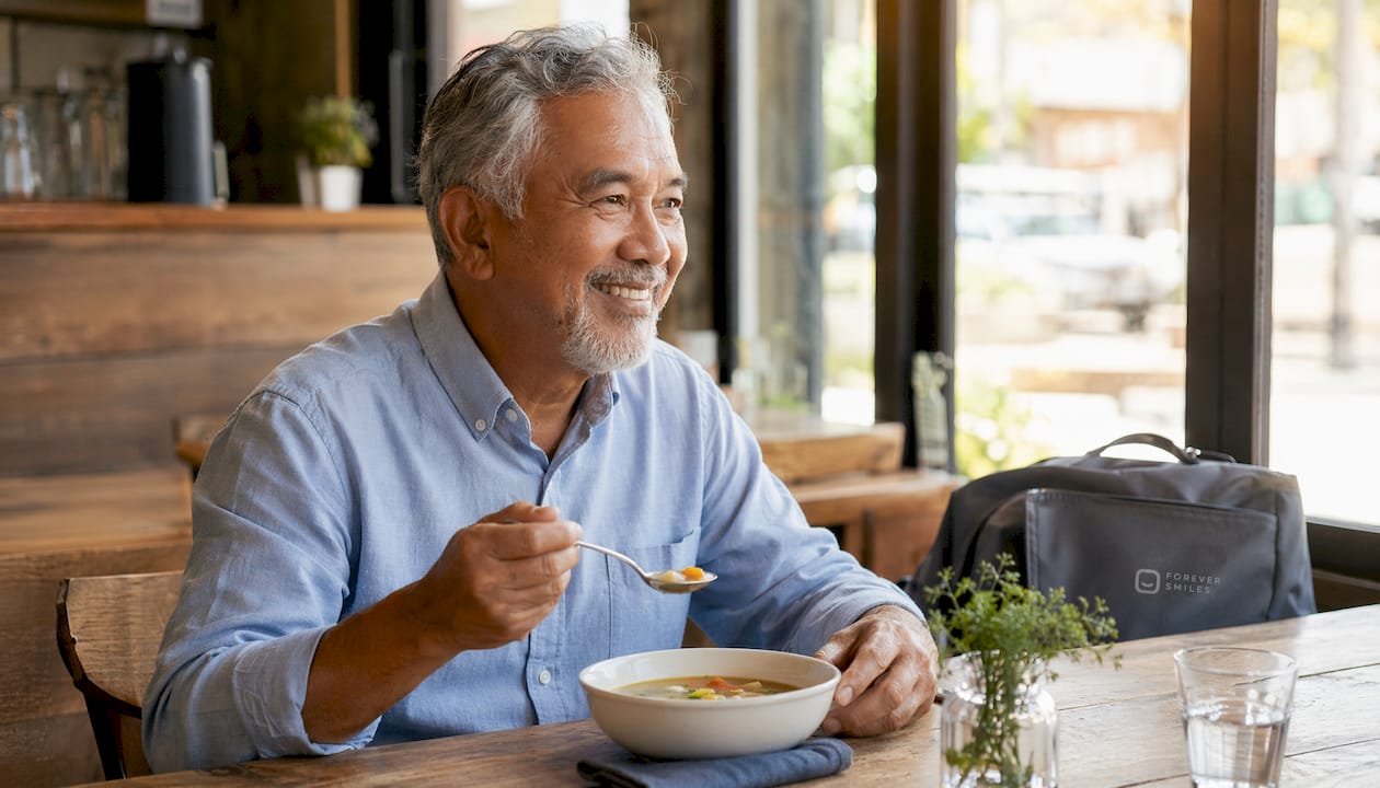 Senior man chewing food comfortably with dental implants