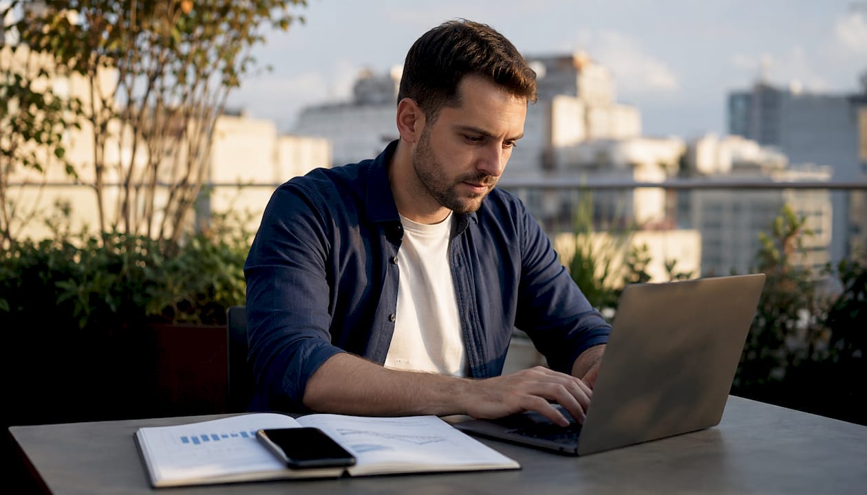 Persona comprobando información desde un portátil y un móvil