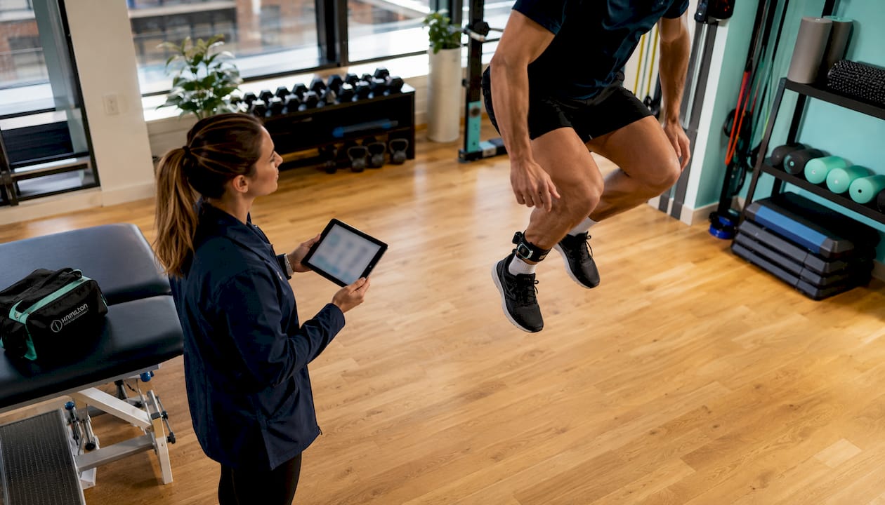 Sports scientist measuring athlete's jump indoors