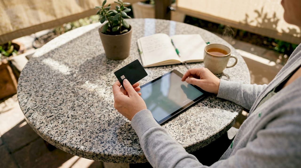 Hands holding card typing on smartphone at café