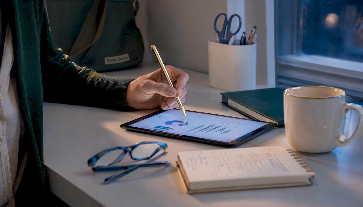 Hand with stylus over tablet in home office