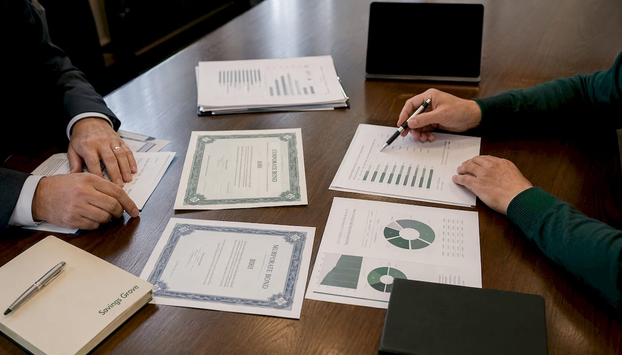 Hands arranging bond investment papers in meeting room