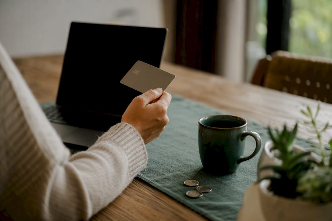 Hand holding generic credit card near wallet and calendar