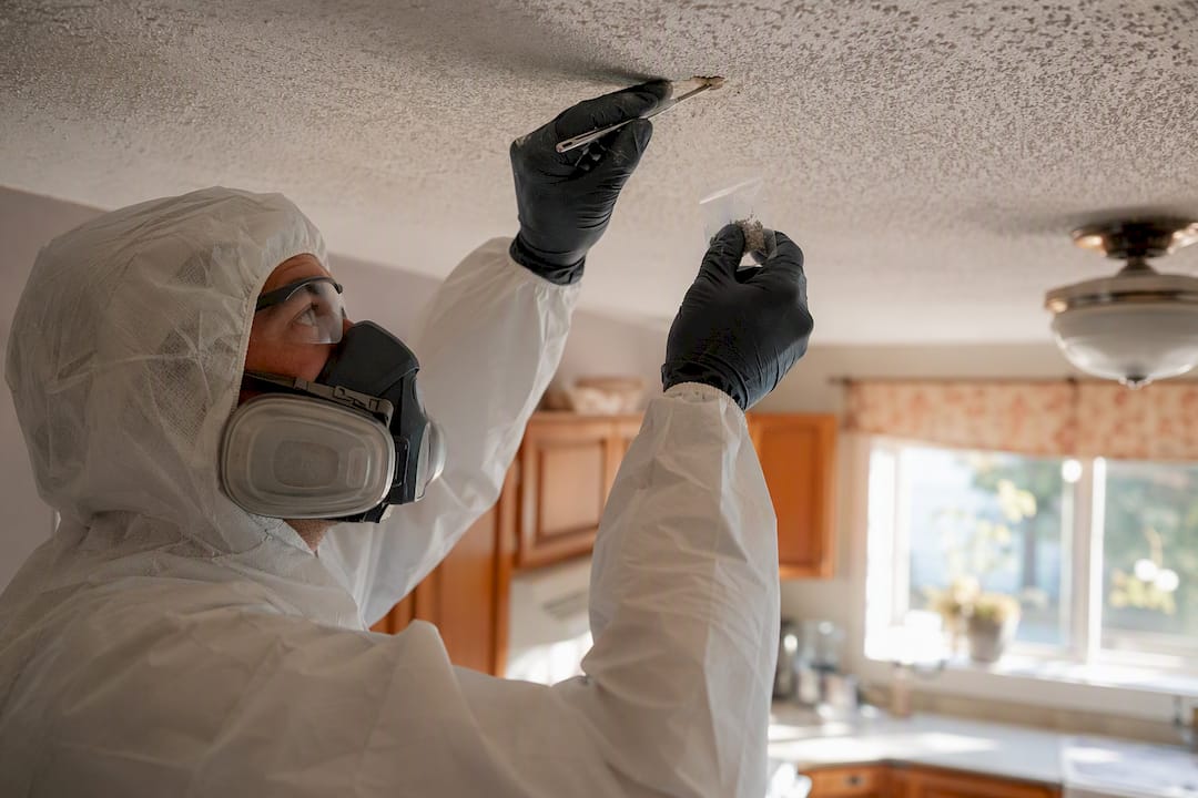 Technician sampling popcorn ceiling for asbestos