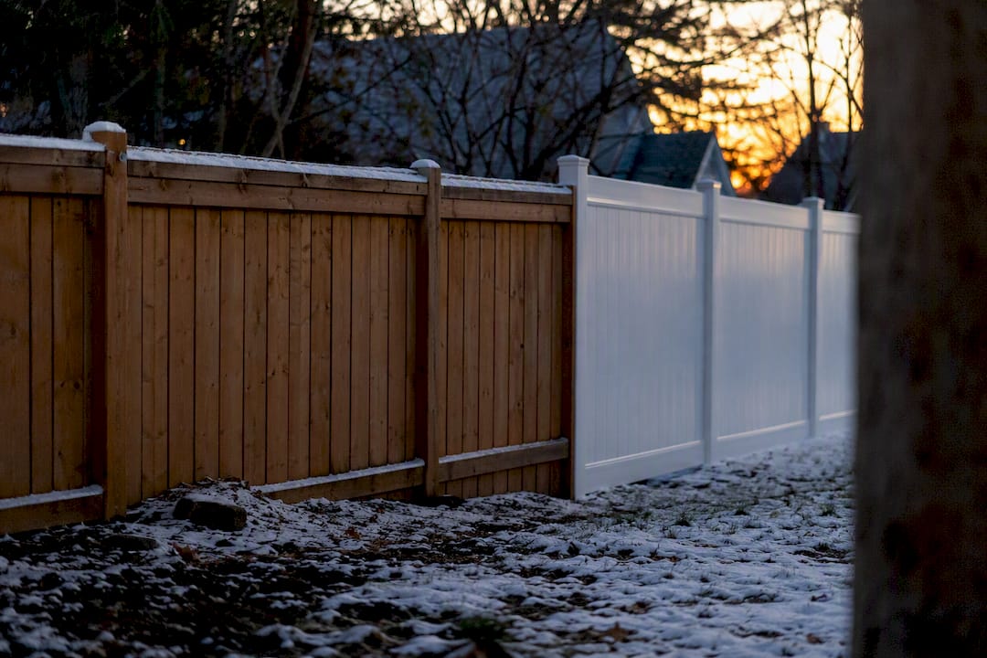 Wood and vinyl fences side by side in snow