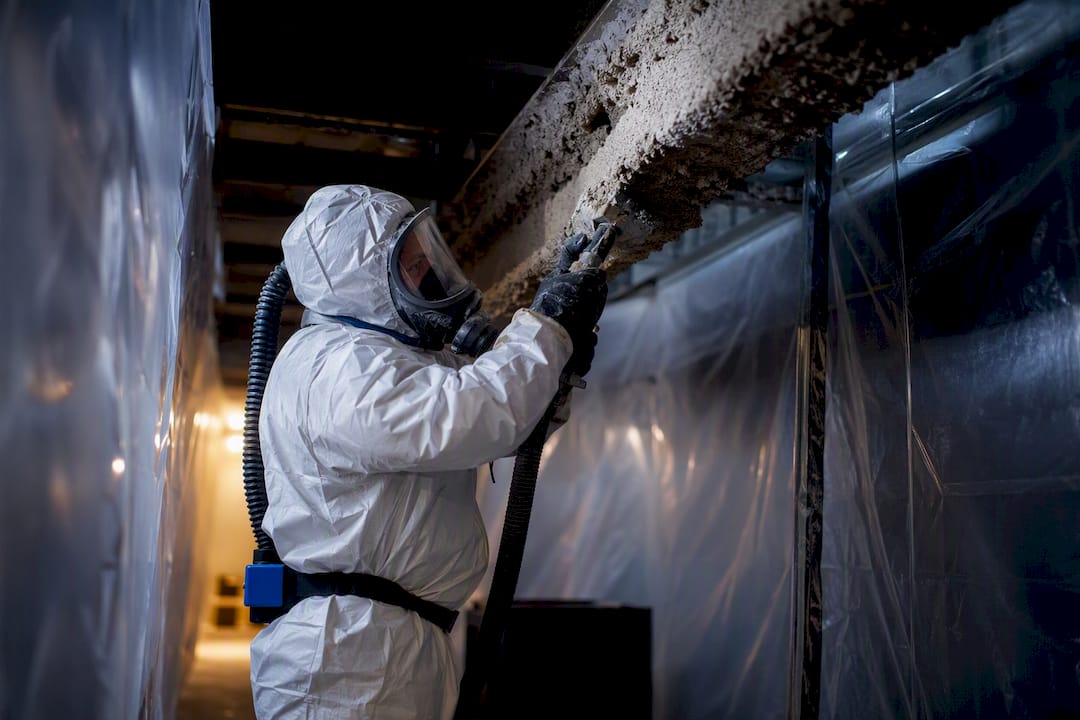 Worker removing asbestos inside sealed containment