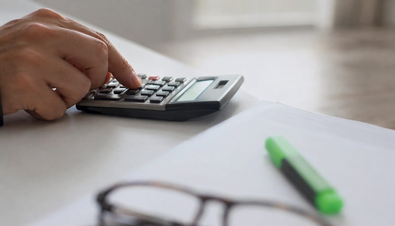 Hand using calculator beside payroll form