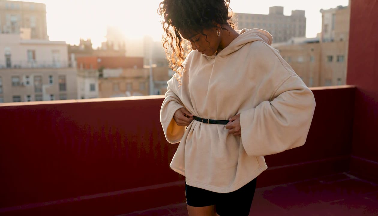 Person styling oversized hoodie with belt at waist