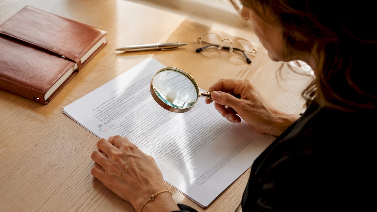 Payer CBD en ligne sécurisé : guide 2026 2 Des mains passent au crible un document juridique sur le CBD à l’aide d’une loupe.