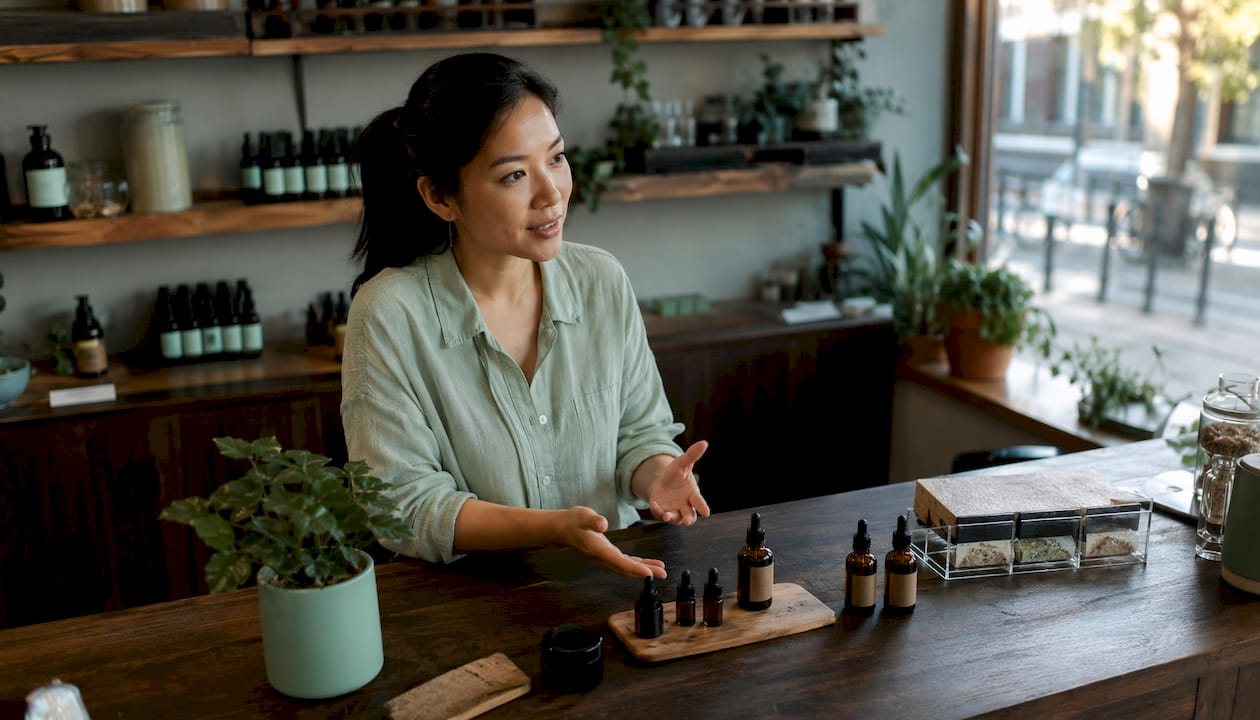 Specialized CBD product advisor welcoming customers at the shop counter.