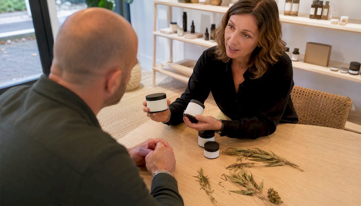 Une conseillère de vente explique à un client les différentes formes de CBD disponibles en magasin.