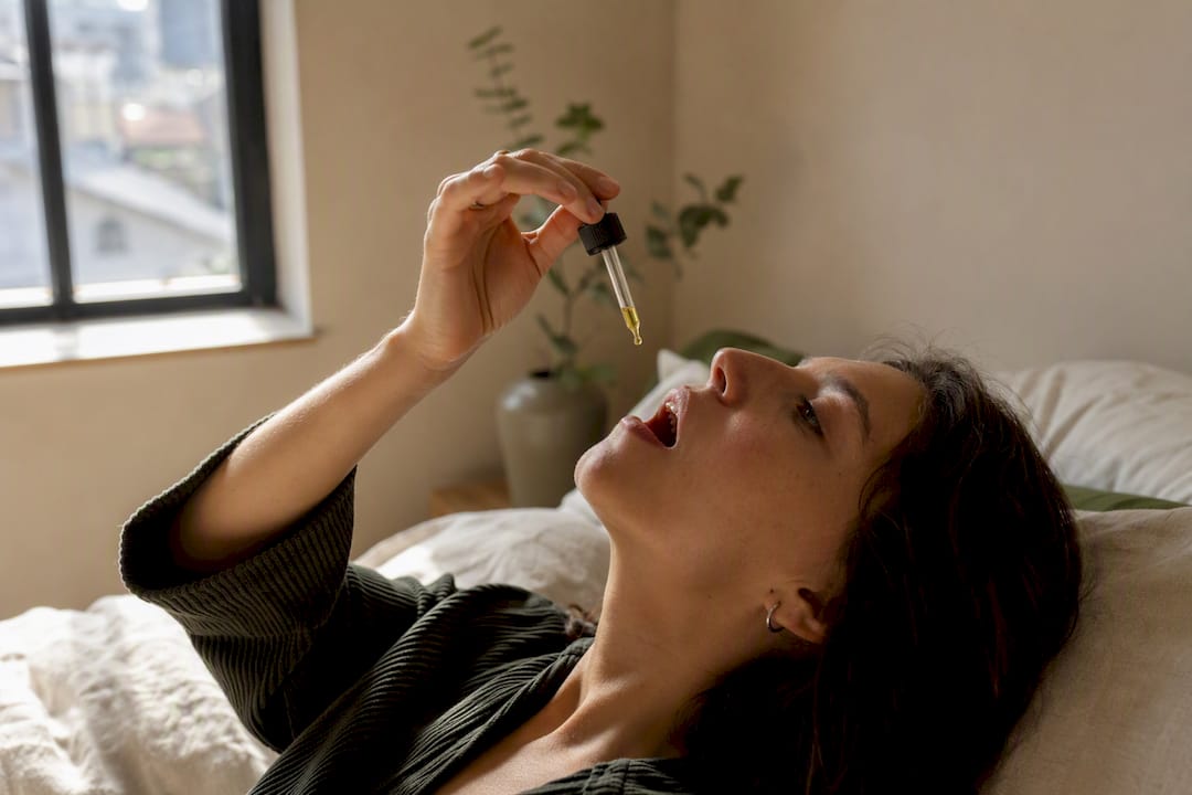 Mains administrant de l'huile de CBD par voie sublinguale