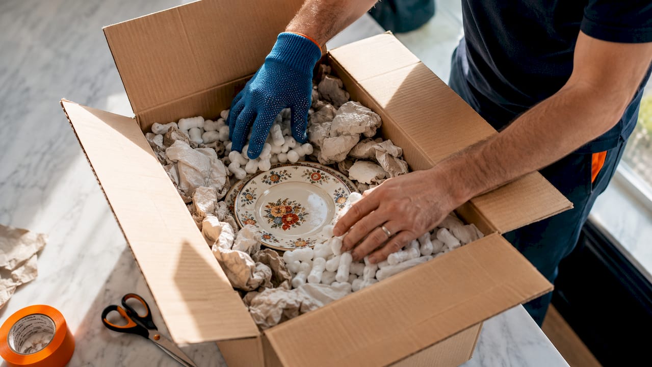 Hands filling void space inside packing box