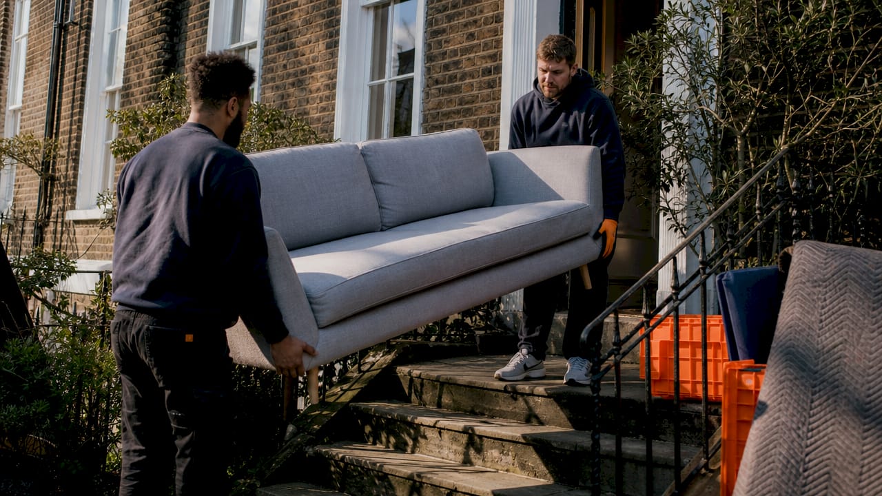 Helpers moving sofa down London flat stairs