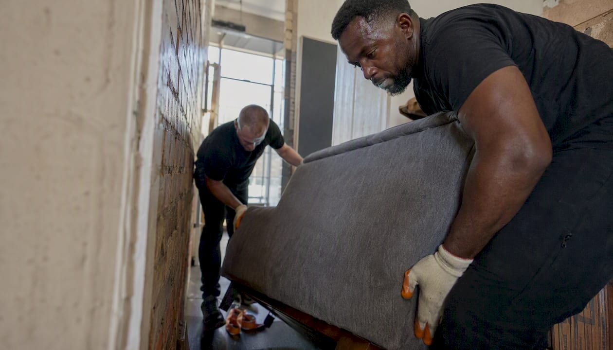 Team lifting bulky sofa on stairwell
