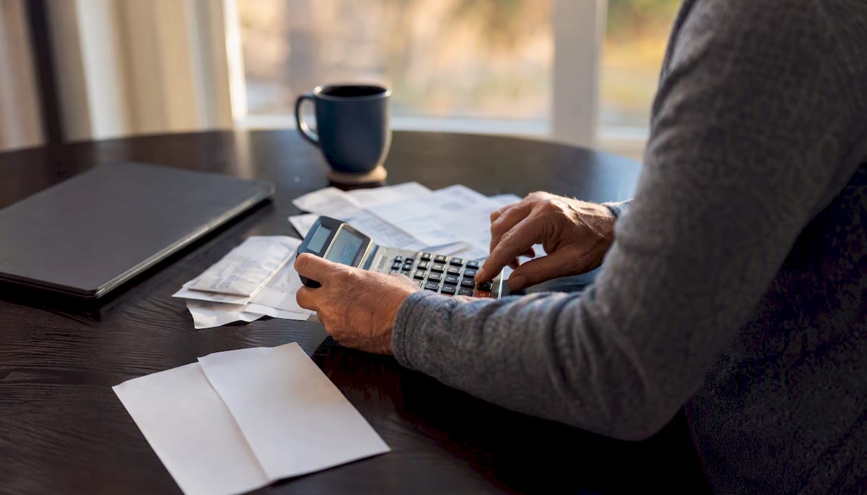 Hands calculating budget with calculator and bills