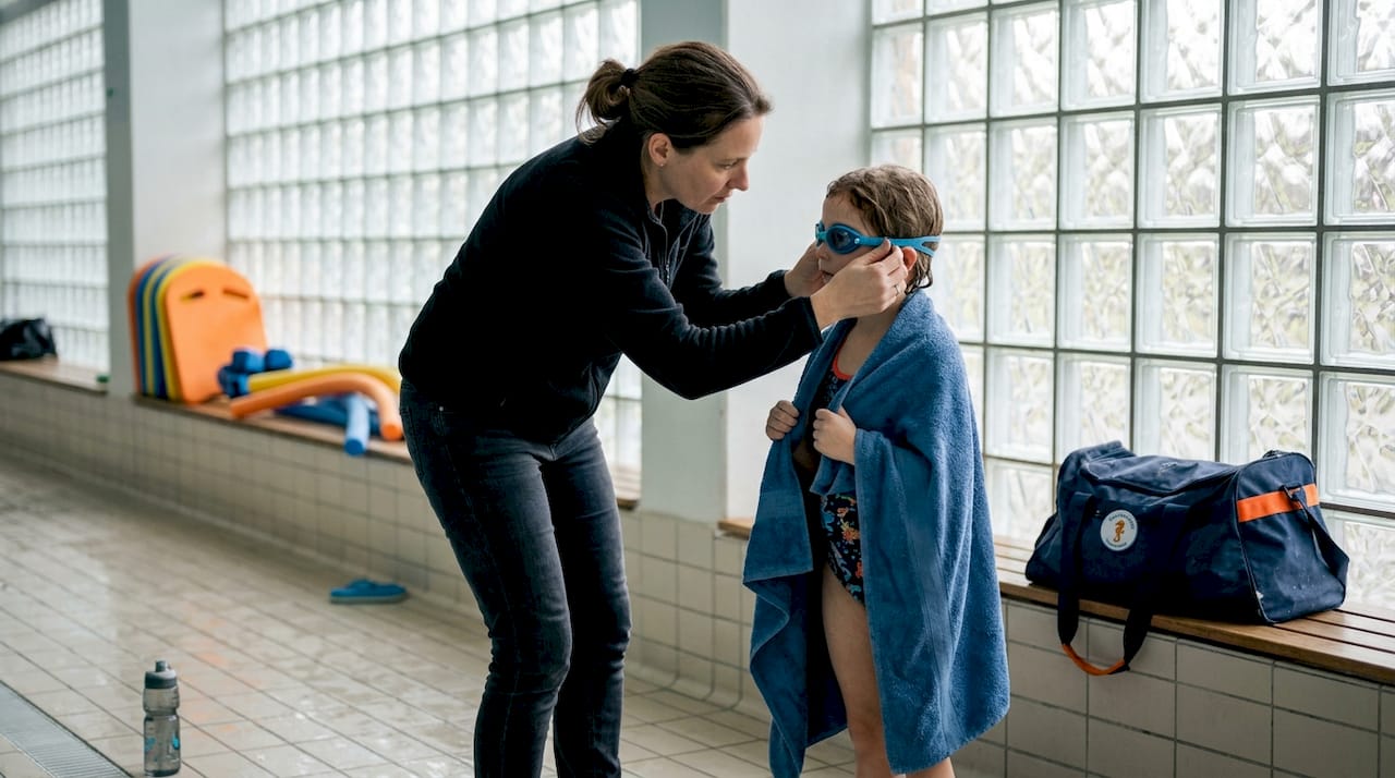 Eine Mutter bringt ihrem Kind das Schwimmen bei.