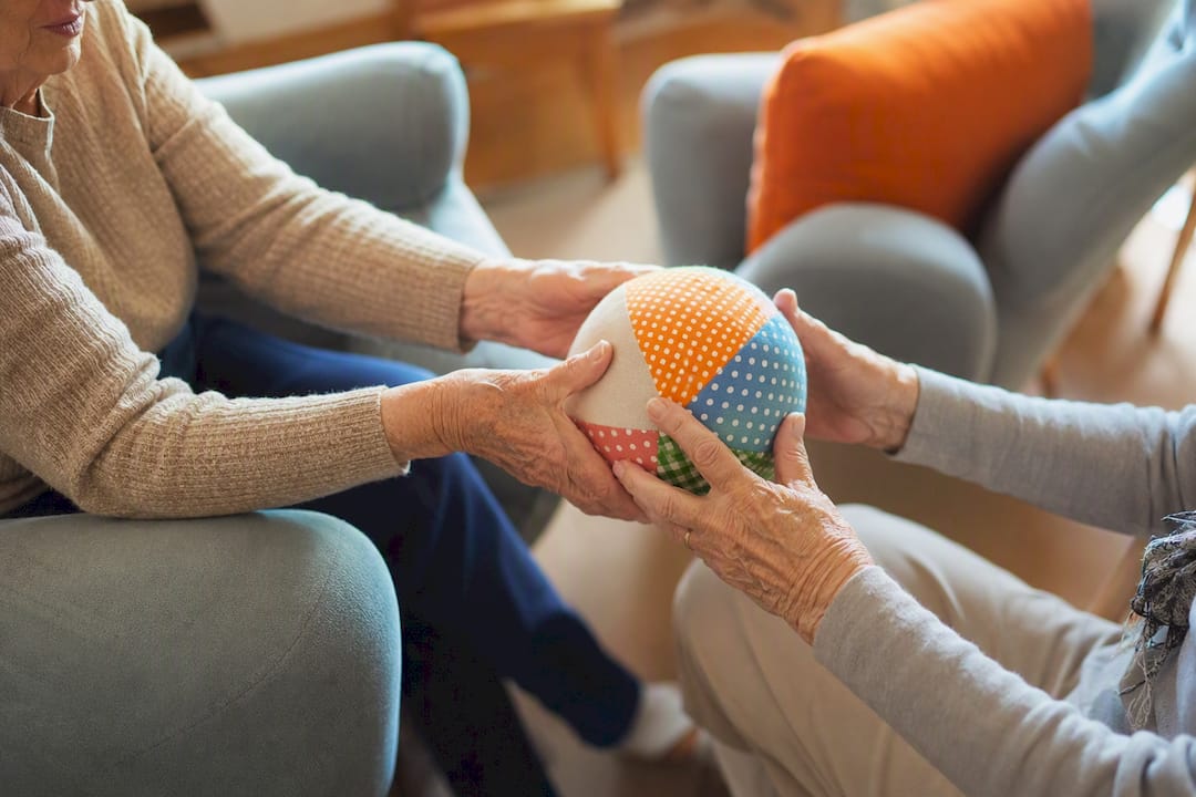 Seniorenhände geben während eines Spiels einen weichen Ball weiter