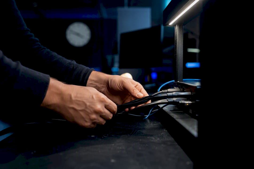 Trader hands adjusting trading cables on dark desk