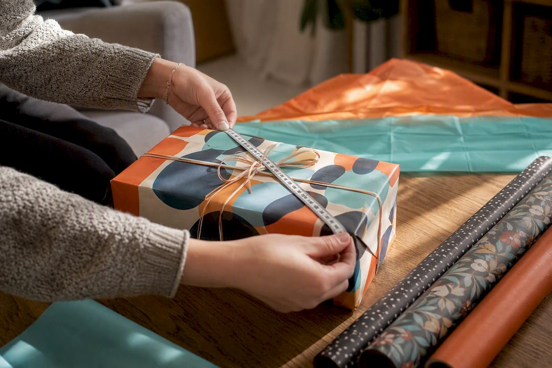 Handen die een cadeauverpakking opmeten met een meetlint