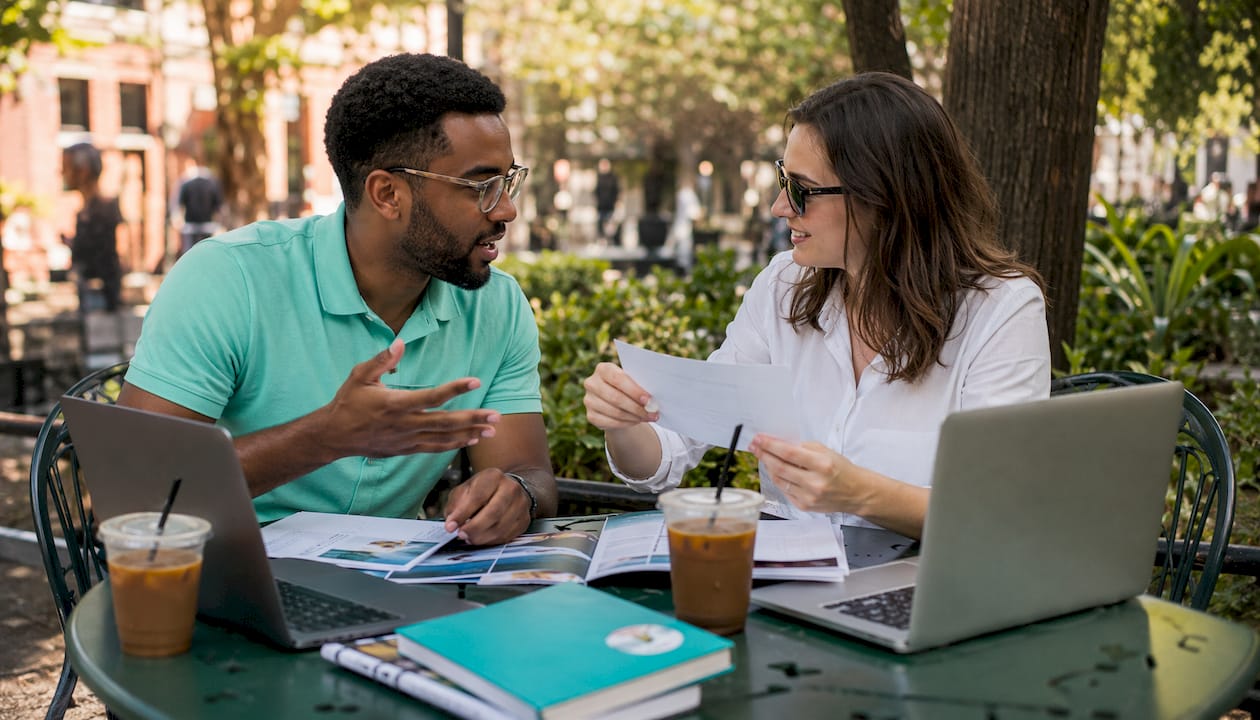 Two colleagues discussing newsletter workflow in café