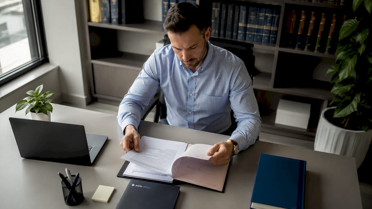 A notary studying a paper file at his office