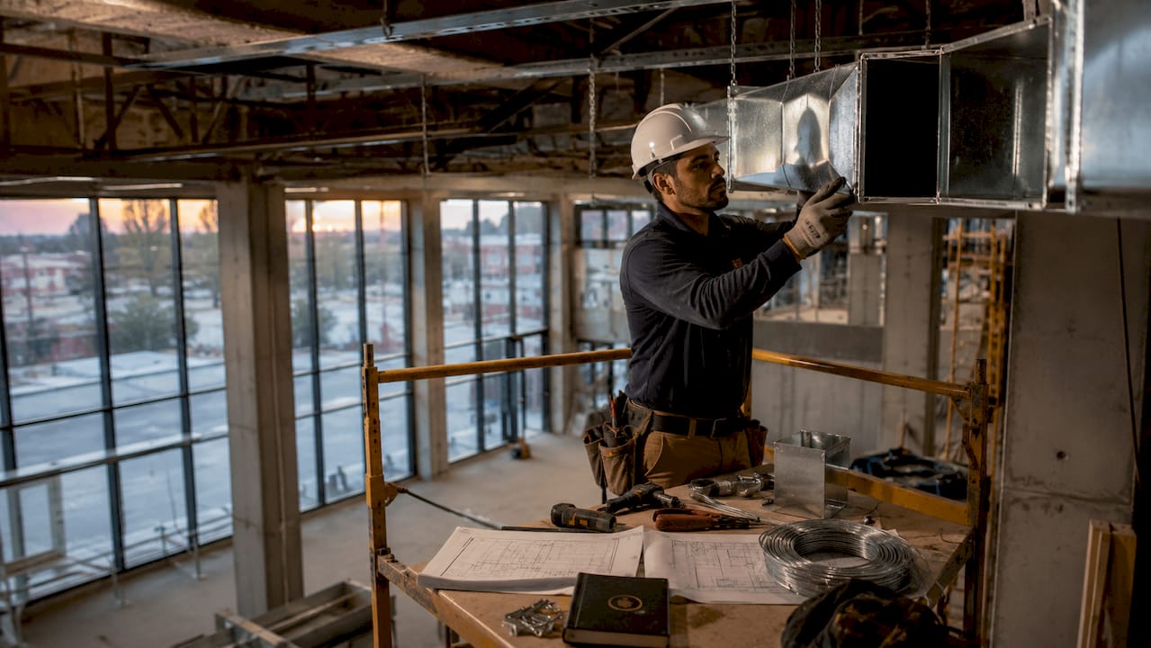 HVAC technician installing ductwork in commercial ceiling