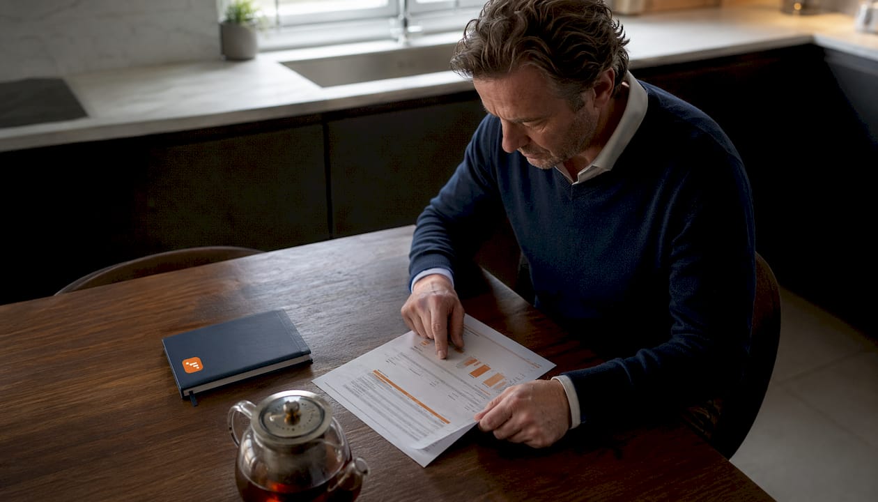 Een man zit aan de eettafel en bestudeert een taxatierapport van een woning.