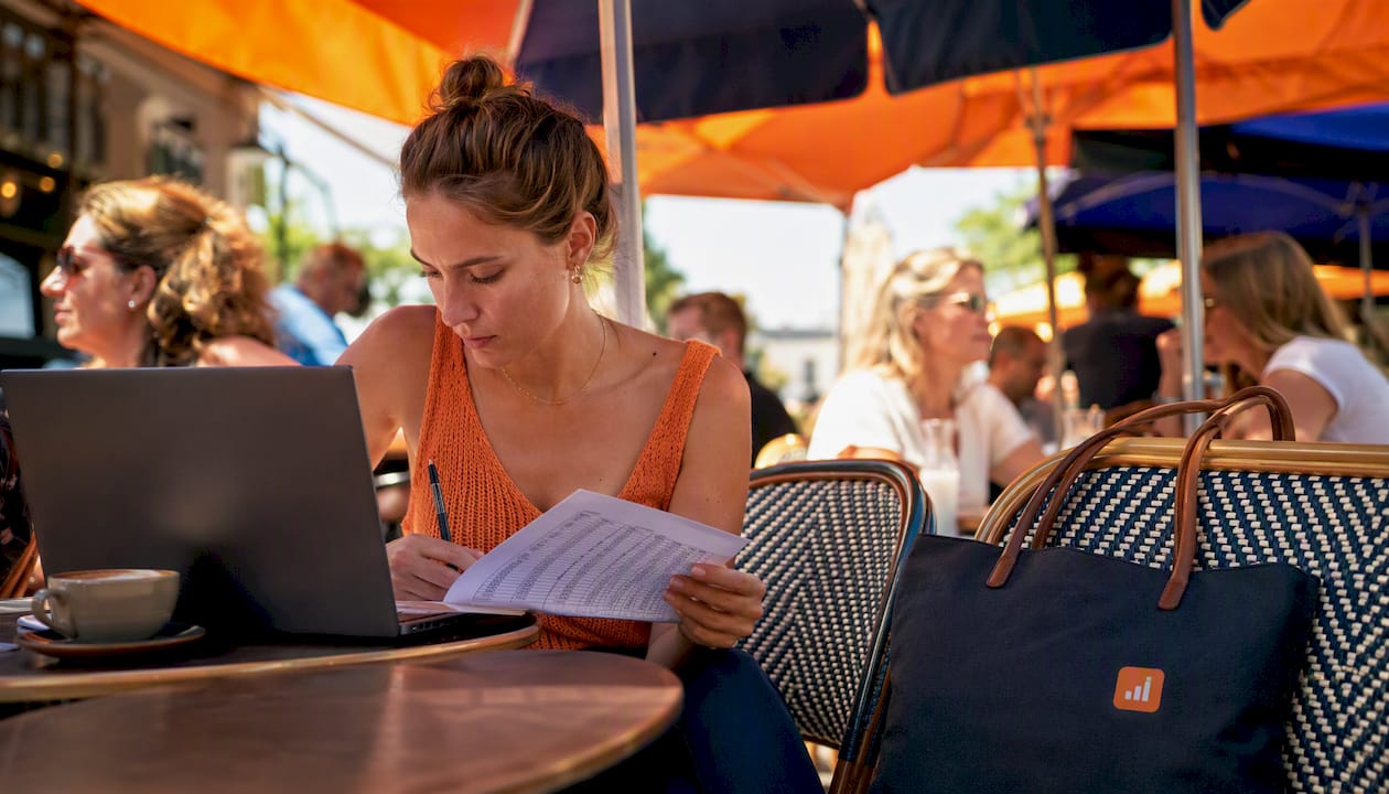 In een gezellig café buigt een vrouw zich over woningdata op haar laptop.