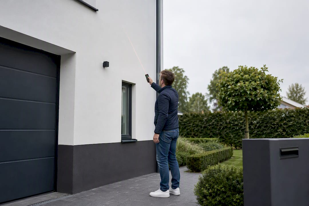 Huiseigenaar die de buitenkant van zijn huis opmeet