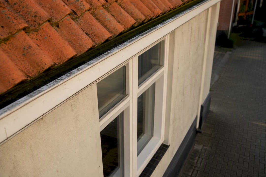Close-up van dakgoot en gerenoveerd raam van huis
