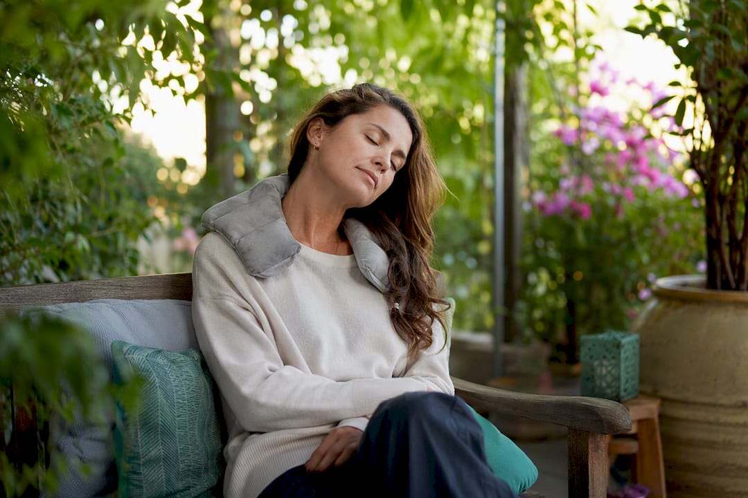 Woman doing neck stretch with heating pad