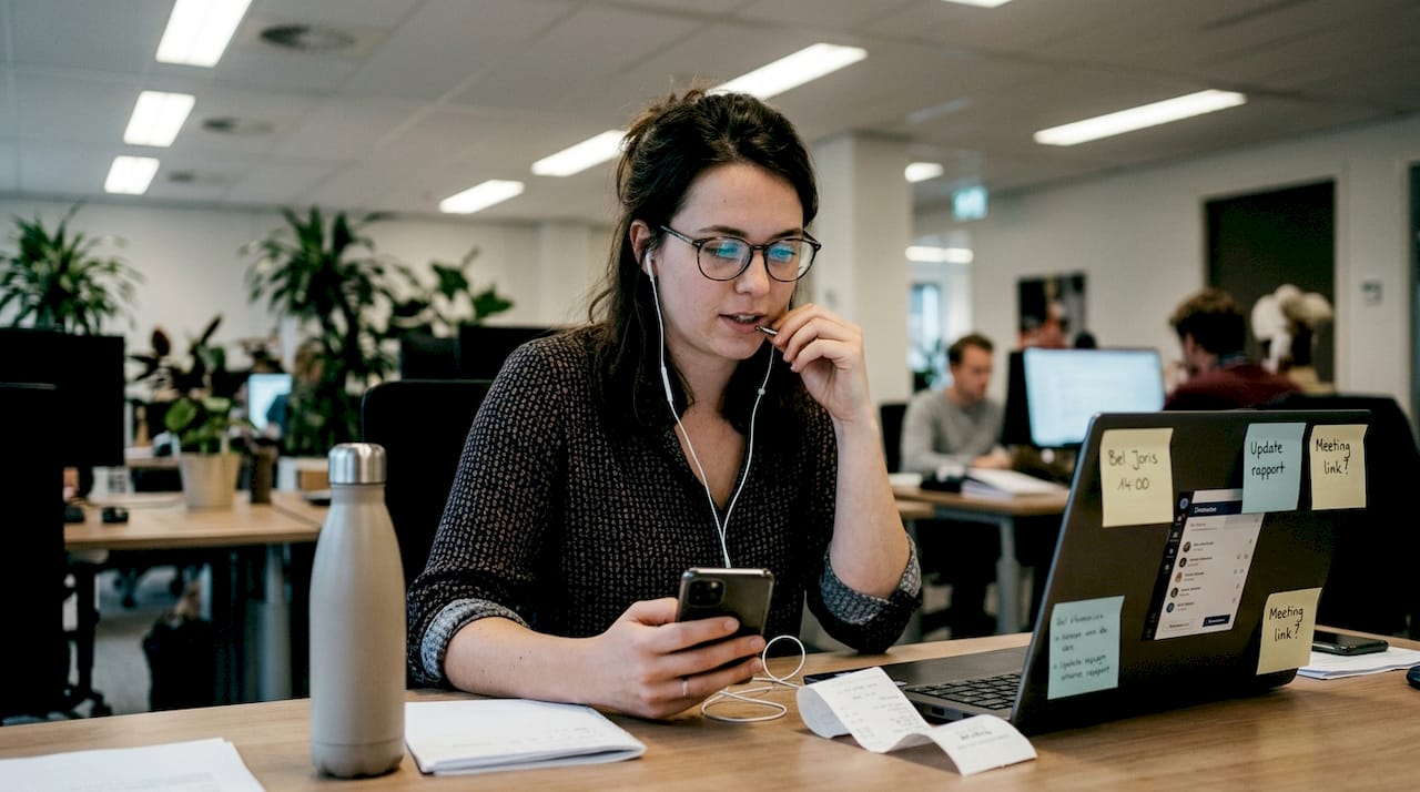Een vrouw voert op haar werk een internationaal telefoongesprek vanaf haar bureau.
