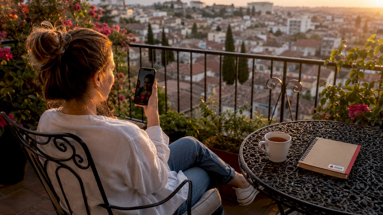 Thuis voert een vrouw een telefoongesprek met haar familie via haar smartphone.