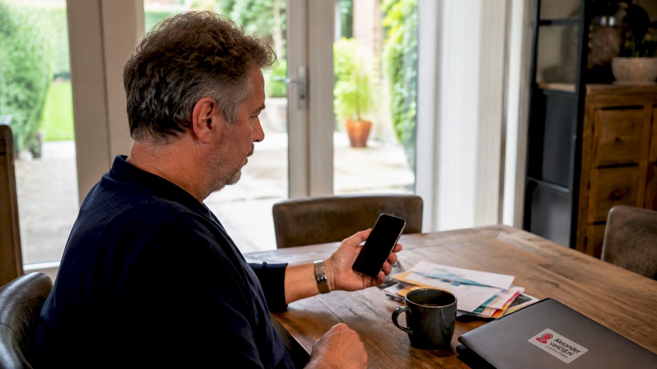 Iemand bekijkt de details van zijn abonnement op zijn telefoon.