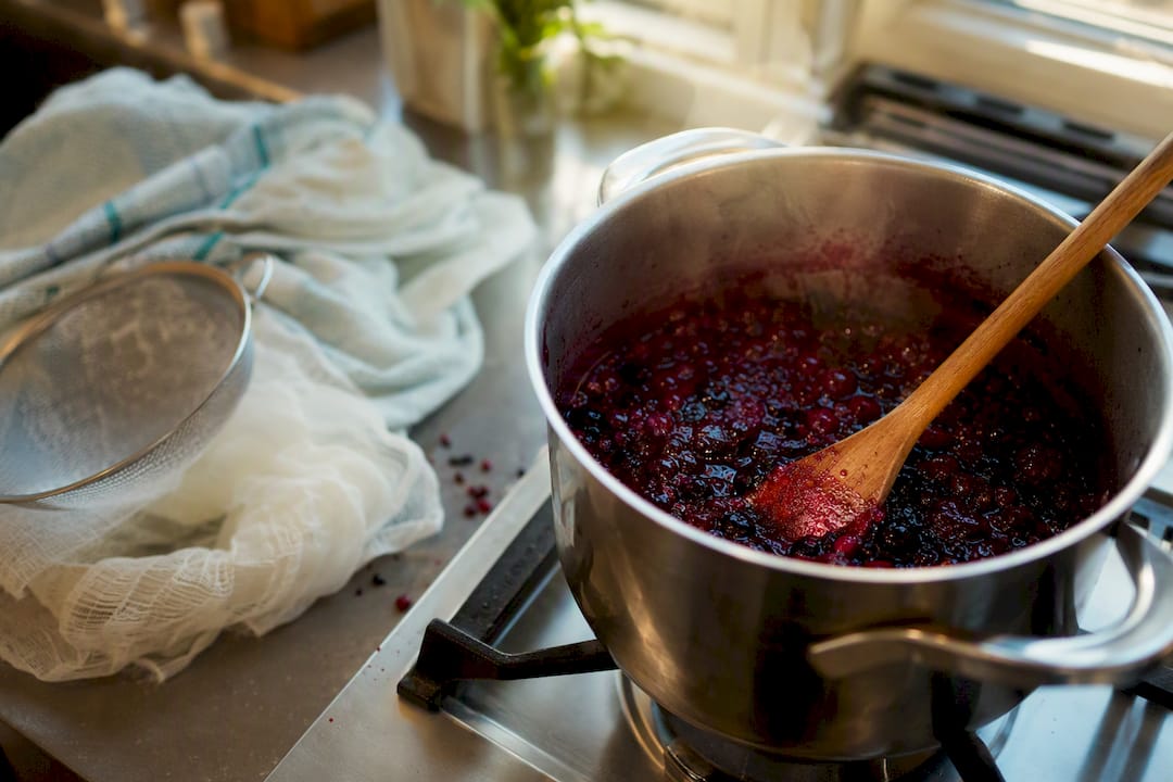 Cooking fruit reduction syrup in pot with wooden spoon