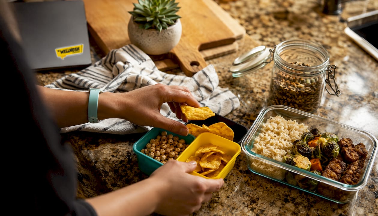 Hands arranging protein snacks with prepped meals